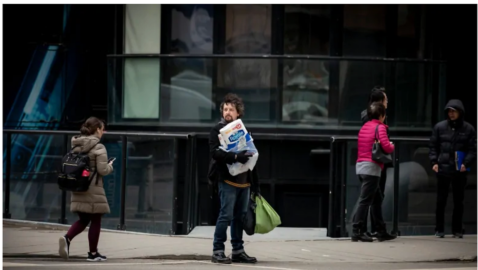 Man on the street holding packaged toilet paper